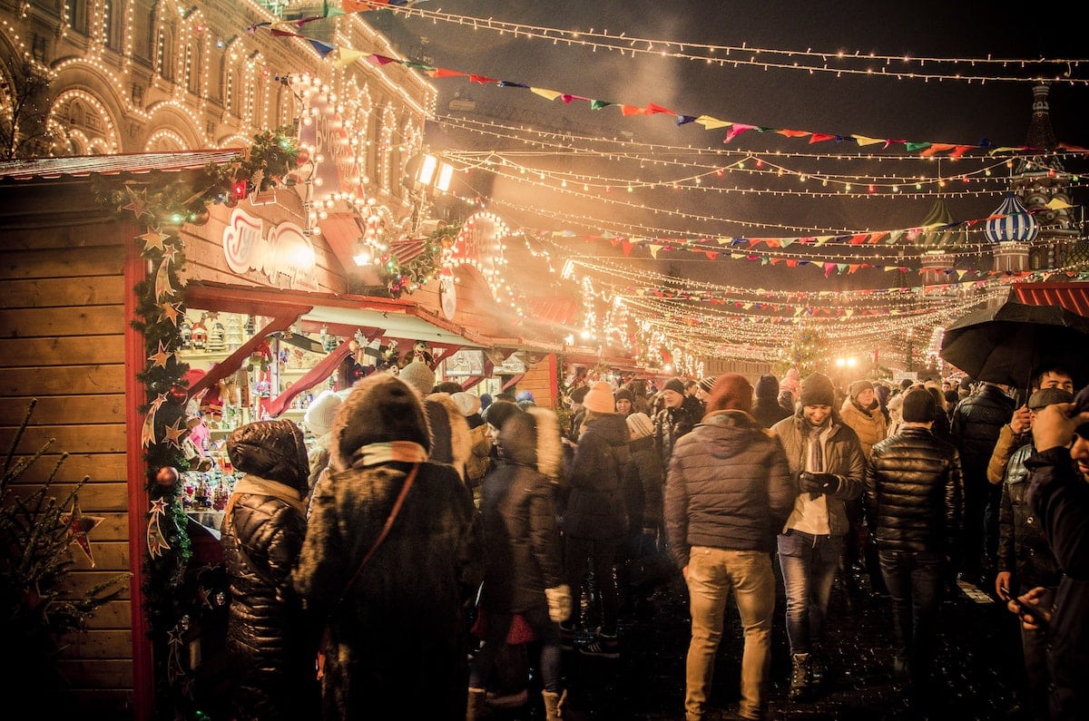 Ein Weihnachtsmarkt voller Leute, die dort arbeiten, sich Glühwein, Baumkuchen und weihnachtliche Musik gönnen.