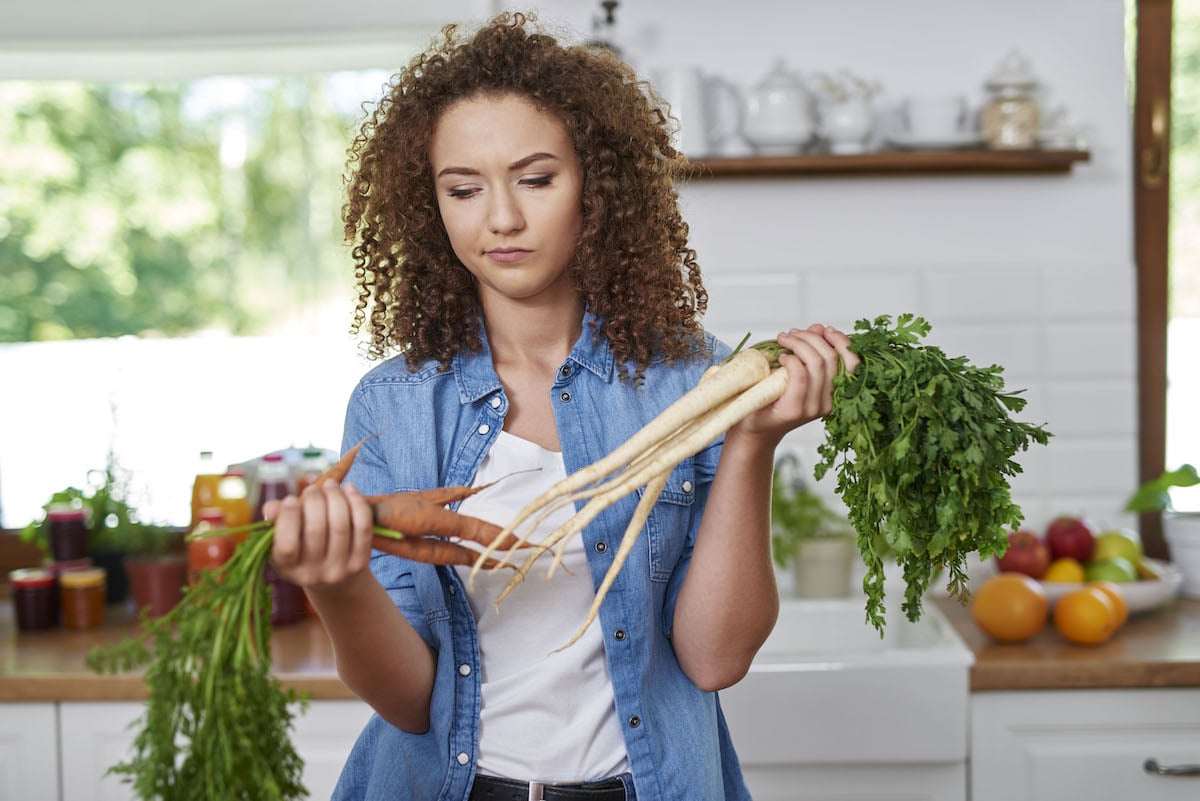 Eine Studentin weiß im März nicht, wie si gut siasonal und regional kochen soll und wiegt eine Karotte ab.