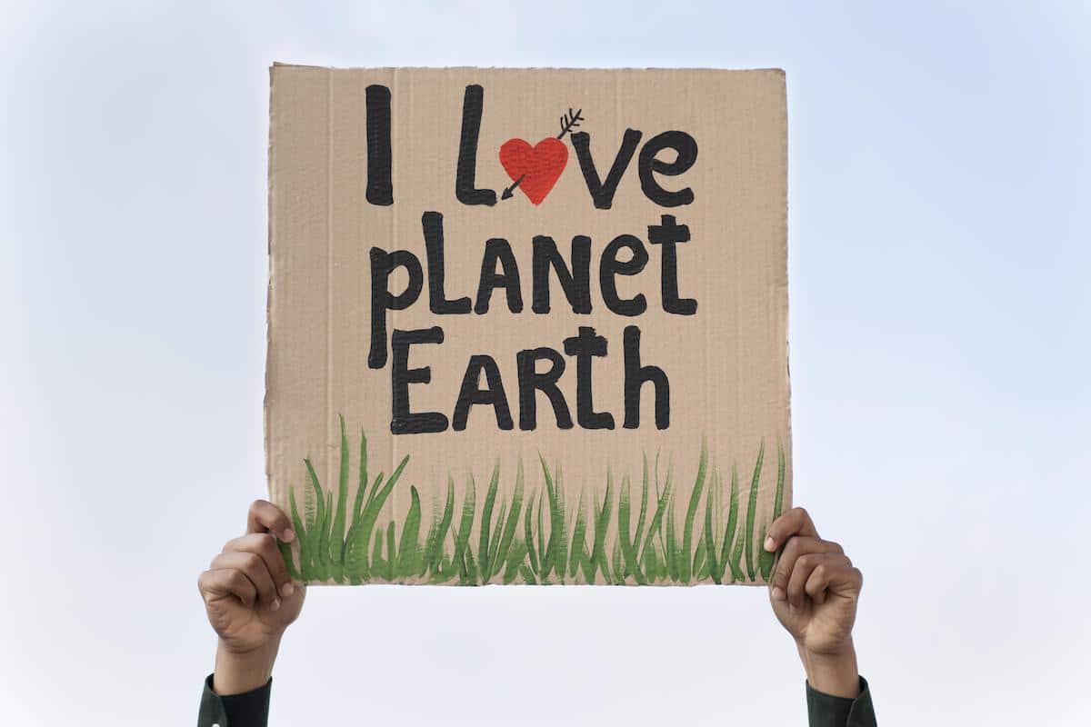 Eine Studierende Person hält ein Schild mit dem Text "I Love Planet Earth" hoch und bewirbt sich für den Fördertopf für klimafreundliche Initiativen der ÖH.